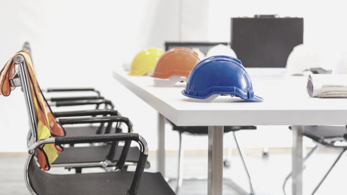 yellow orange and blue safety helmets on white desk next to black chairs
